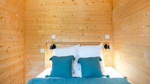 Ein Zimmer mit Holzwänden, einem Bett, zwei Nachttischen und einer Wandleuchte.