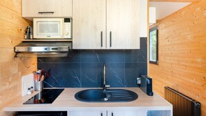 Eine moderne Küche mit Holzschränken, einer schwarzen Arbeitsplatte, einer eingebauten Mikrowelle und einem schwarzen Spülbecken.