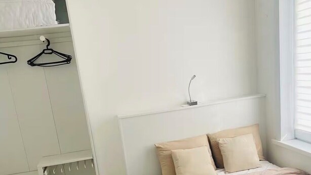 Une chambre à coucher avec un lit, une armoire et une fenêtre.