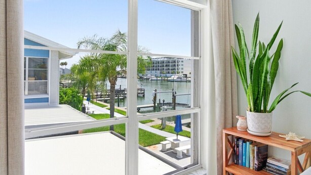 A room with a large window overlooking a marina, a bookshelf, and a potted plant. - Cozy Beachside Condo With Intracoastal Water Views (Madeira Beach)