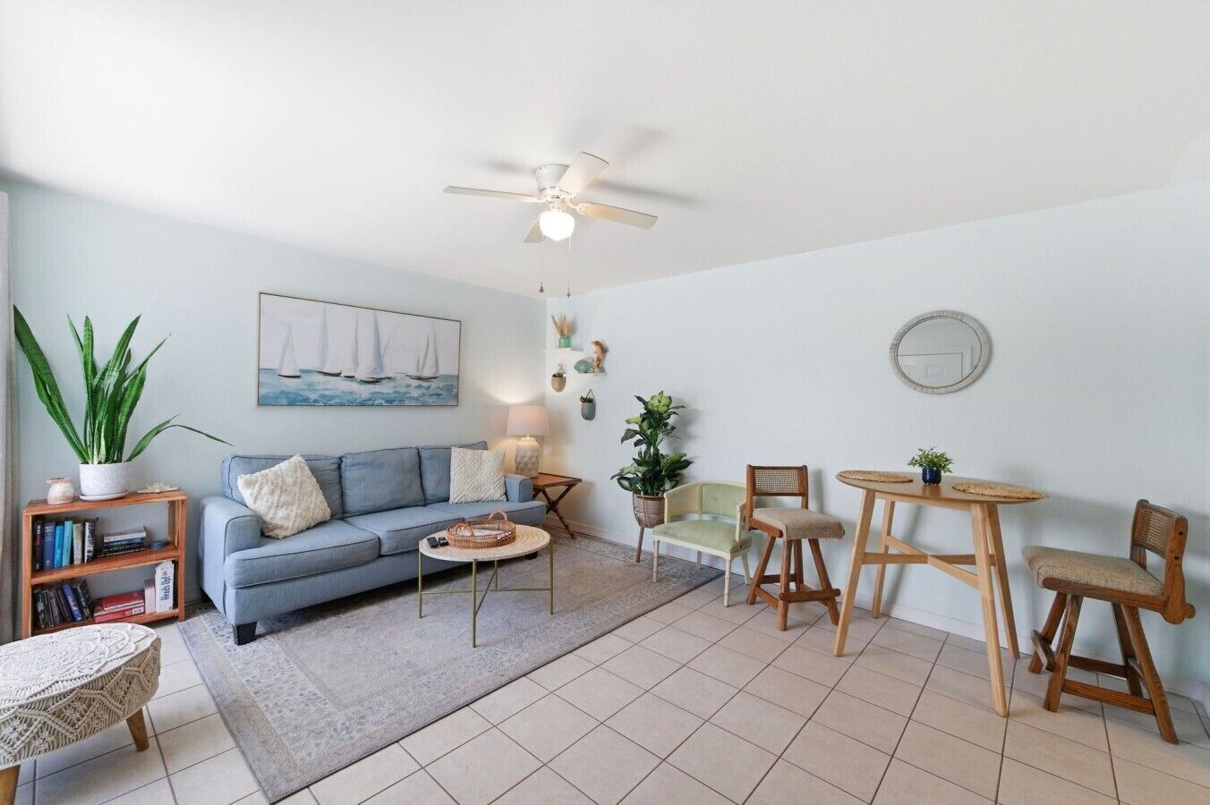 Un salon comprenant un canapé, une table basse, une table à manger avec des chaises, une bibliothèque et un ventilateur de plafond.