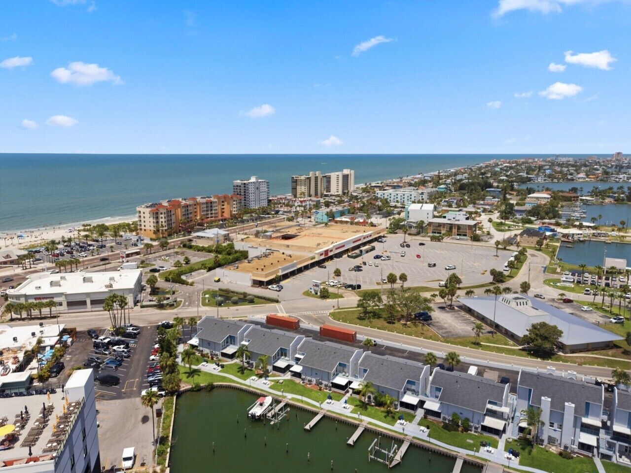 Un paisaje urbano costero con un puerto deportivo, edificios y una playa.