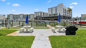 A marina with boats, a building with balconies, and a grassy area with benches. - Cozy Beachside Condo With Intracoastal Water Views (Madeira Beach)