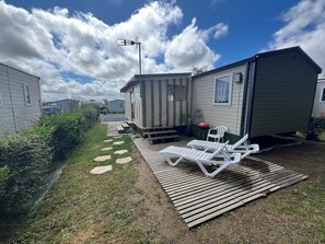 Une maison mobile dotĂ©e dâun patio, dâun barbecue et dâune antenne parabolique.
