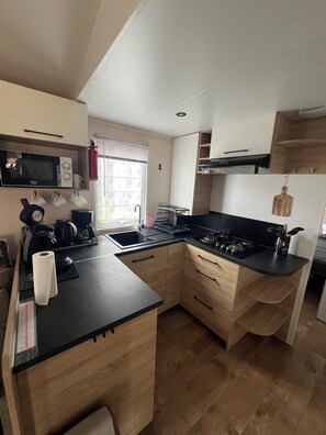Een kleine keuken met een magnetron, koffiezetapparaat en spoelbak.