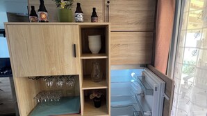 A compact kitchen with wooden cabinets, a built-in wine cooler, and a refrigerator. - Mobil-Home 417 6 persons (Litteau)