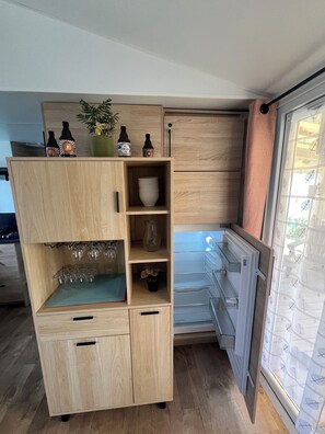 Een compacte keuken met houten kastjes, een geïntegreerde wijnkoeler en een koelkast.