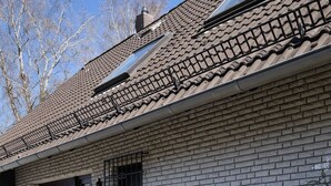 Ein modernes Haus mit Ziegelaußenwand, einem Ziegeldach und einer kleinen Außenbereich-Sitzgelegenheit mit Pflanzen und einer Laterne.