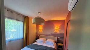 A bedroom with a bed, bedside tables, a hanging light fixture, and a wall-mounted light. - T2 Puy de Dôme Chic, Cozy & Ideally Located (Clermont-Ferrand)