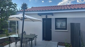A patio area with a table and chairs, a covered seating area, a door, and a window. - T2 Puy de Dôme Chic, Cozy & Ideally Located (Clermont-Ferrand)