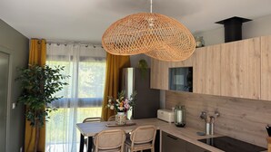 A modern kitchen with a wooden countertop, a built-in oven, and a hanging woven light fixture. - T2 Puy de Dôme Chic, Cozy & Ideally Located (Clermont-Ferrand)