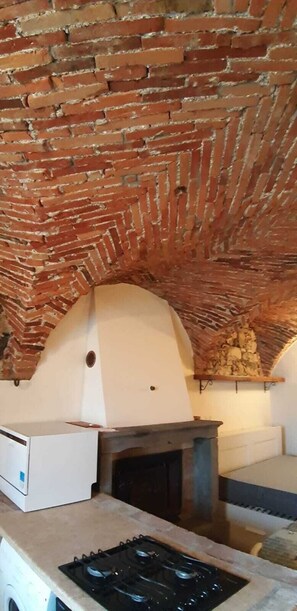 Ein Backofen aus Ziegeln mit steinernen Fundament, einer weißen Arbeitsplatte und einem Gasherd.