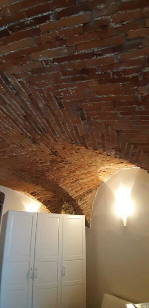Ein Zimmer mit Ziegeldecke, weißem Wandschrank und an der Wand befestigten Leuchten.