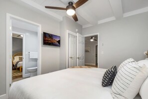 A bedroom with a bed, a ceiling fan, a night light, and a cityscape painting on the wall. - Downtown Haven|Patio|Near Dining (Vista)