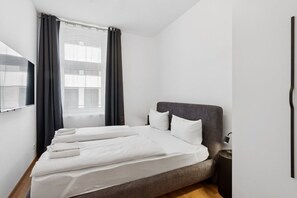 A modern hotel room with a bed, a bedside table, a mirror, and a window with curtains. - Arbio I Modern Art Suite for 6 (Leipzig)