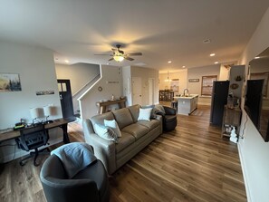 A spacious living area with a sofa, a dining table, and a kitchen in the background. - Brand New Townhome, 3 Bed/2.5 Bath Close to Furman, NGU, SRT & Greenville! (Greenville)