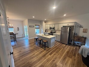 A modern kitchen with a central island, stainless steel appliances, and a bar area. - Brand New Townhome, 3 Bed/2.5 Bath Close to Furman, NGU, SRT & Greenville! (Greenville)