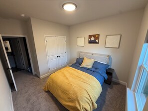 Ein Schlafzimmer mit einem Bett, einer Tür und einem Fenster.