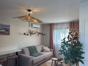 A living room with a sofa, a small table, a plant, and a ceiling fan.