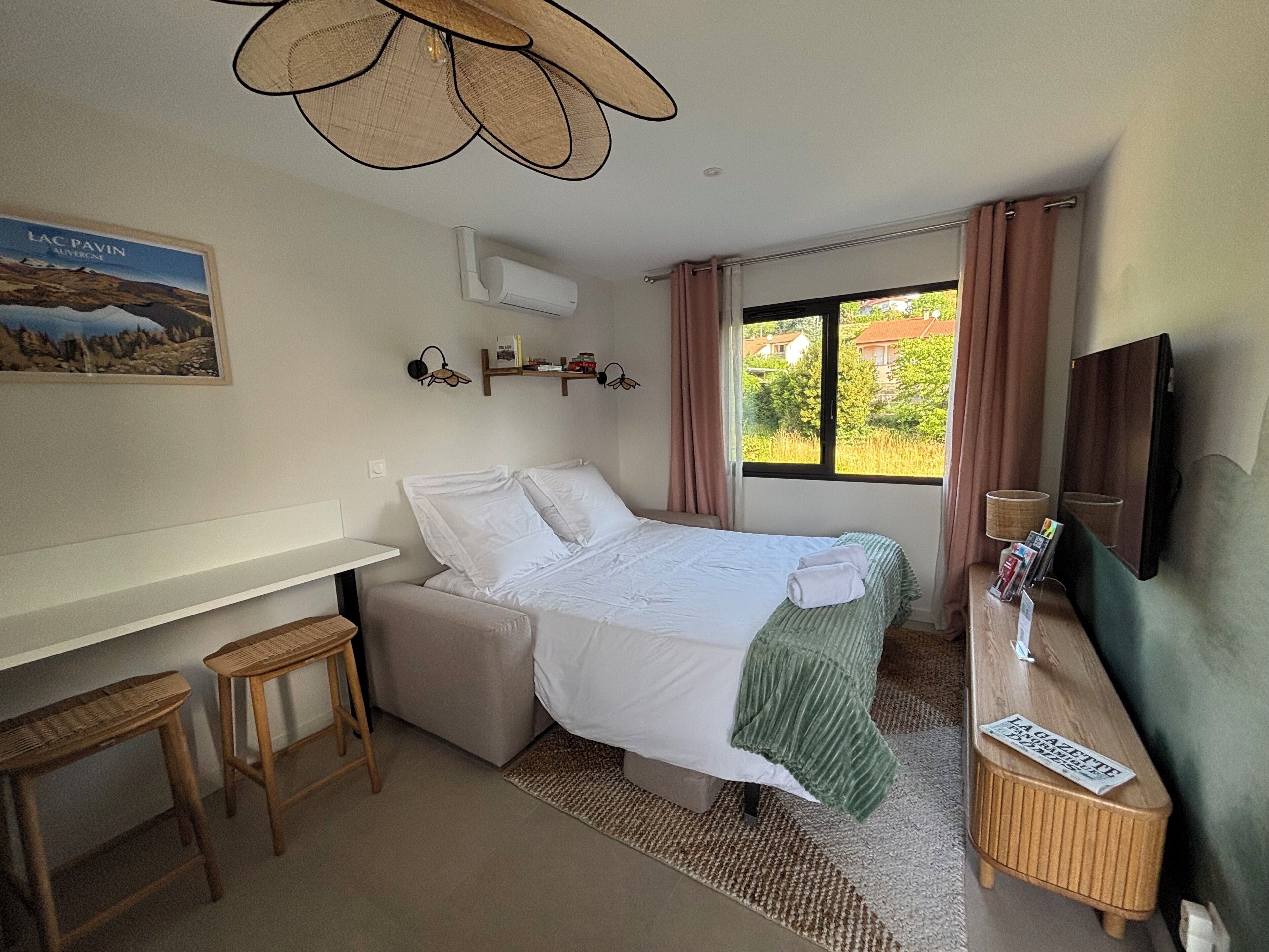 A hotel room with a bed, a desk, a chair, a TV, and a window with curtains.