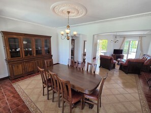 Un comedor con una gran mesa de madera y sillas, un aparador y una araña.