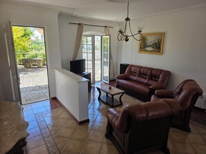 A living room with a sofa, a coffee table, a TV, and a painting on the wall. - House with private pool in the heart of the Douro - ideal for families (Paços)