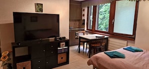 Una habitación compacta con televisión, una mesa de comedor y una cama.