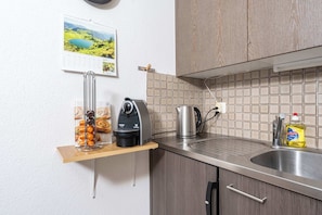 A kitchen with a coffee maker, kettle, and dish soap on the counter.