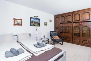 A bedroom with a bed, a chair, a wardrobe, and wall-mounted pictures. - Cozy Alpine Studio in Wiriehorn with Parking (Diemtigen)