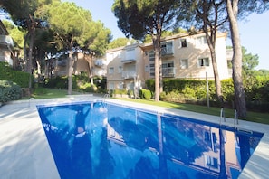 Una piscina envoltada d'arbres i edificis d'apartaments.