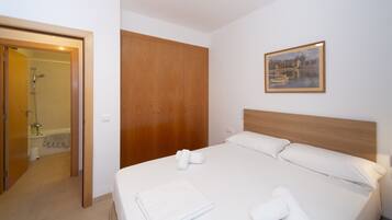 Una habitación de hotel con cama, un armario de madera, un cuadro en la pared y zona de ducha.