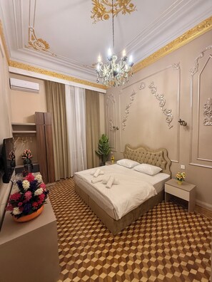 A hotel room with a checkered floor, a bed with white linens, a chandelier, and a mirror. - Crown Palace Hotel Baku (Baku)