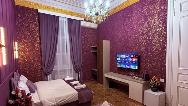 Quarto de hotel com duas camas, televisão, minibar e lustre.
