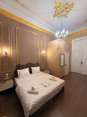 A hotel room with a large bed, a chandelier, and a mirror on the wall. - Crown Palace Hotel Baku (Baku)