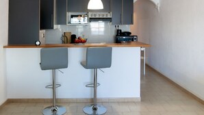 A modern kitchen with grey cabinets, a white countertop, and two bar stools. - WELCS APARTMENT 380 EMP with terrace and parking (Empuriabrava)