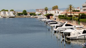 A marina with boats docked along a waterfront, surrounded by buildings with Mediterranean architecture. - WELCS APARTMENT 380 EMP with terrace and parking (Empuriabrava)