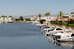 A marina with boats docked along a waterfront, surrounded by buildings with Mediterranean architecture. - WELCS APARTMENT 380 EMP with terrace and parking (Empuriabrava)