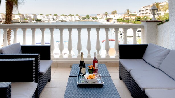 A balcony with wicker furniture, a tray with drinks and snacks, and a view of a marina. - WELCS APARTMENT 380 EMP with terrace and parking (Empuriabrava)