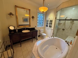 Un baño con una bañera grande, un tocador con espejo, un inodoro y una zona de ducha.