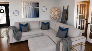 Ein modernes Wohnzimmer mit einer Eckcouch, Wanddekoration und Holzboden.