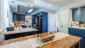 A modern kitchen with blue cabinets, a black refrigerator, and a coffee maker on the counter.
