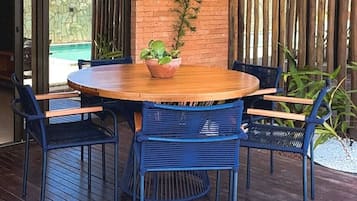 Ein runder Holztisch mit einem Blumentopf in der Mitte, umgeben von vier blauen Stühlen.