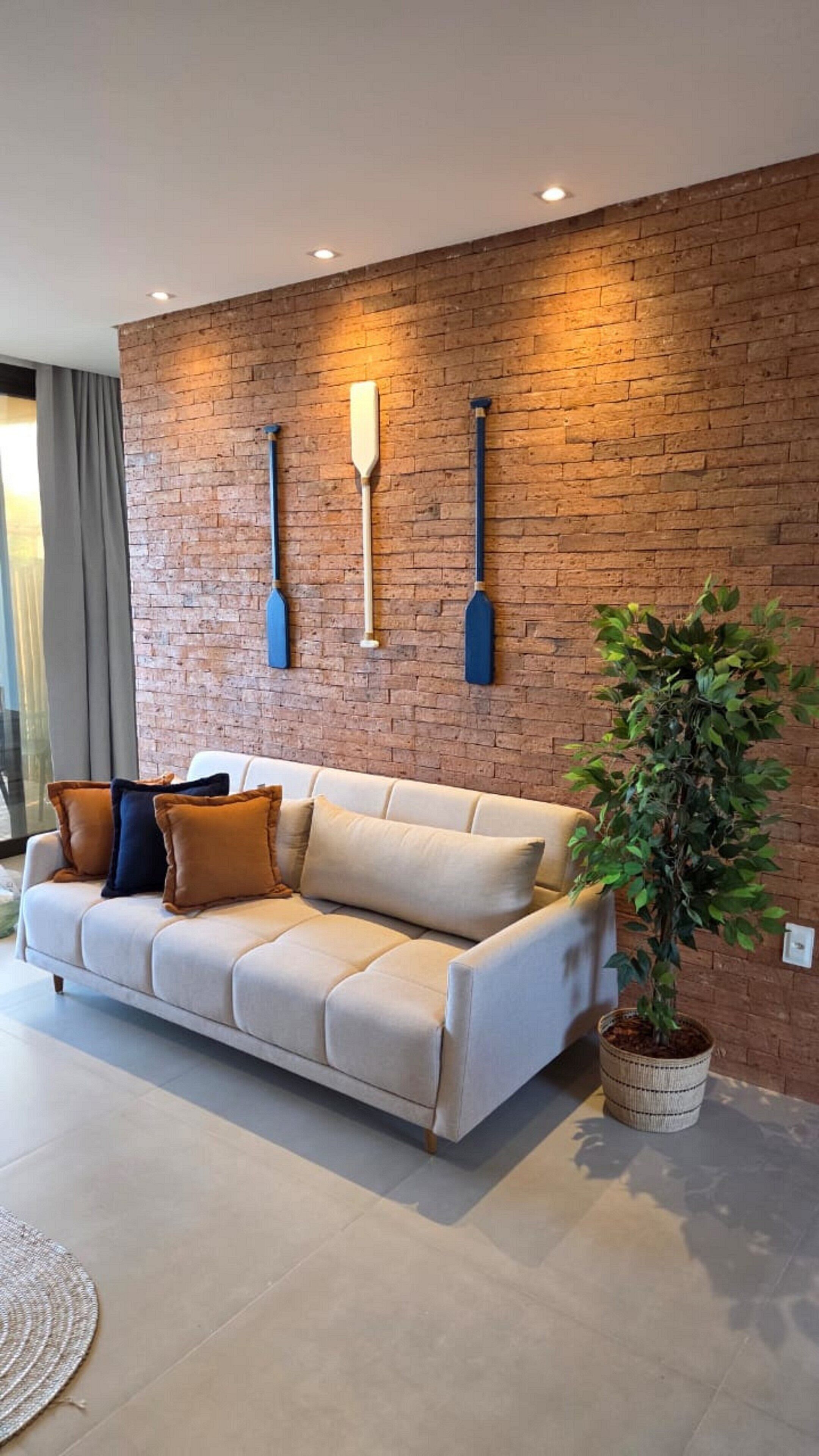 A modern living room with a brick wall, a sofa, and a potted plant.