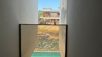 A narrow corridor with a view of a building and a small outdoor area with a stone wall and a plant.