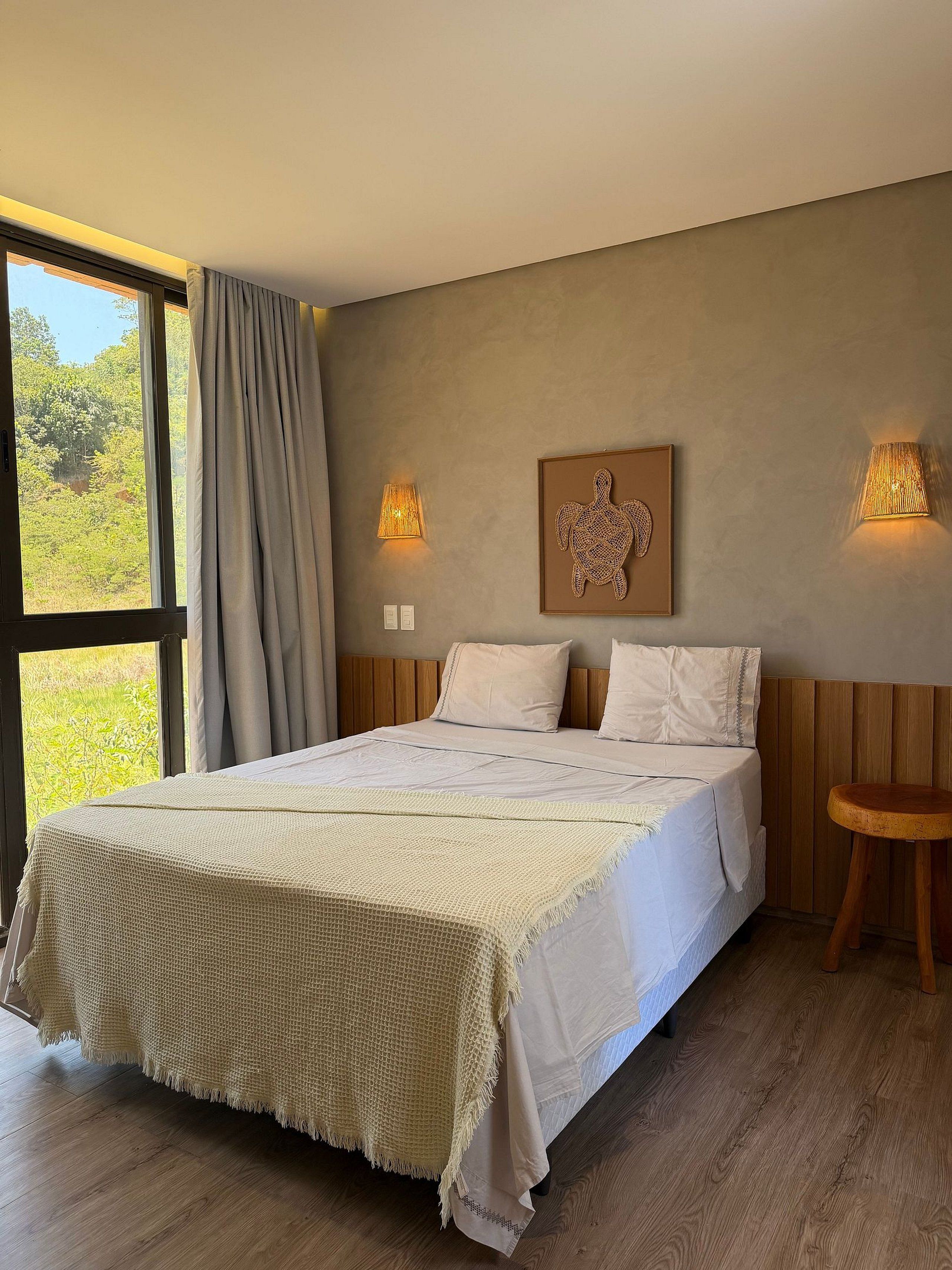 Een slaapkamer met een groot bed, twee wandlampen en een raam met gordijnen.