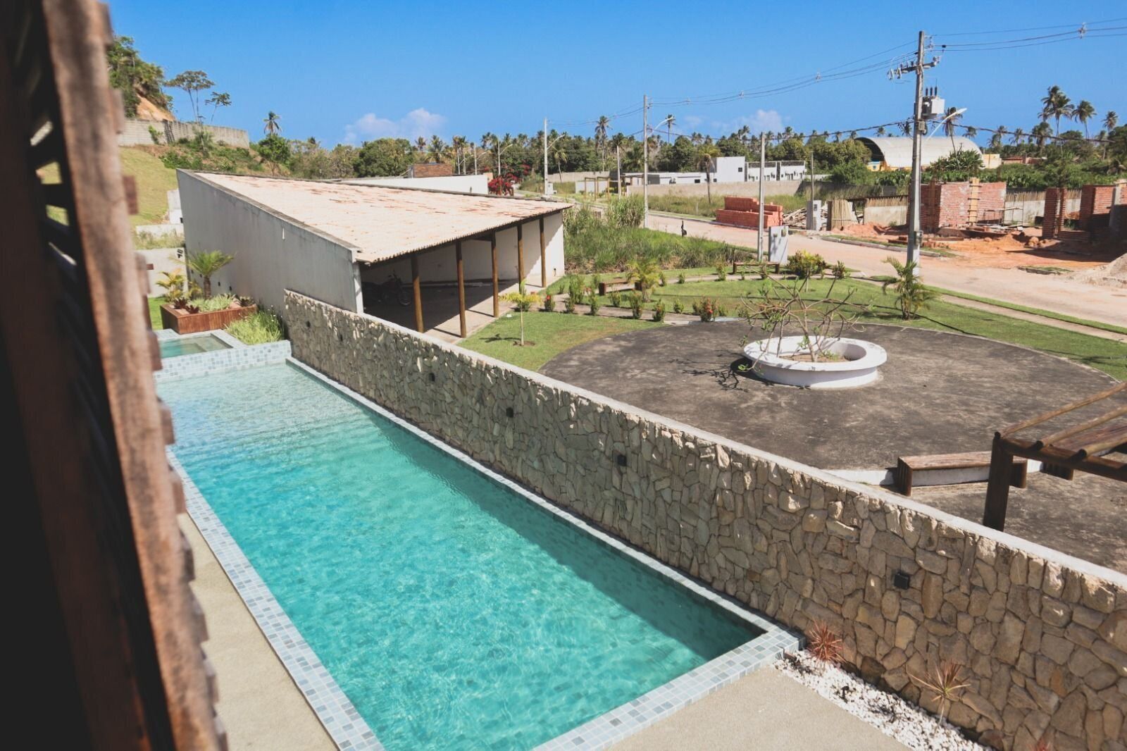 A swimming pool with a stone wall and a covered area with a dome roof.