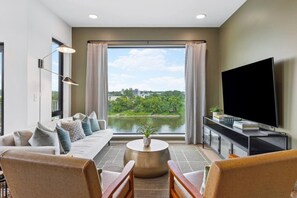 Un salon moderne avec un canapé, des fauteuils, un téléviseur et une vue sur un lac.