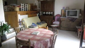 Un'area pranzo con tavolo, sedie, divano, televisione e mobile.