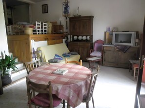 Ein Essbereich mit Tisch, Stühlen, einer Couch, einem Fernseher und einem Schrank.