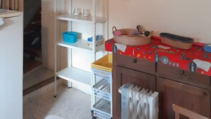 Una cucina con una tovaglia rossa, un termosifone bianco e uno scaffale con utensili da cucina.